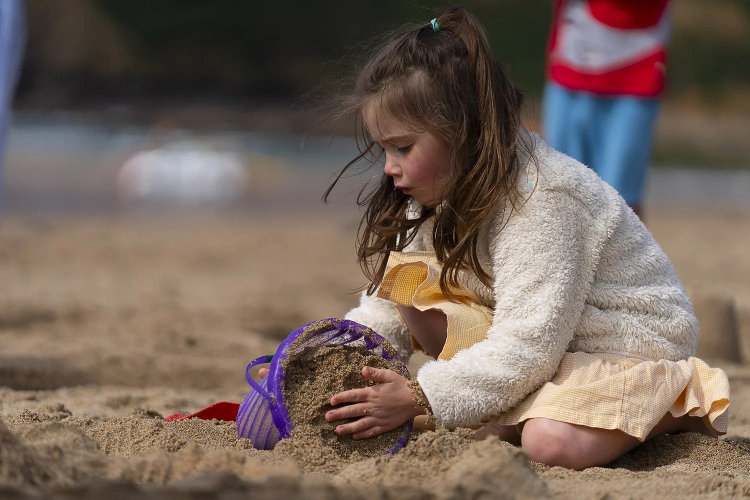 Young girl building a sandcastle on a west Cornwall beach, photographed without posing by Lee Searle