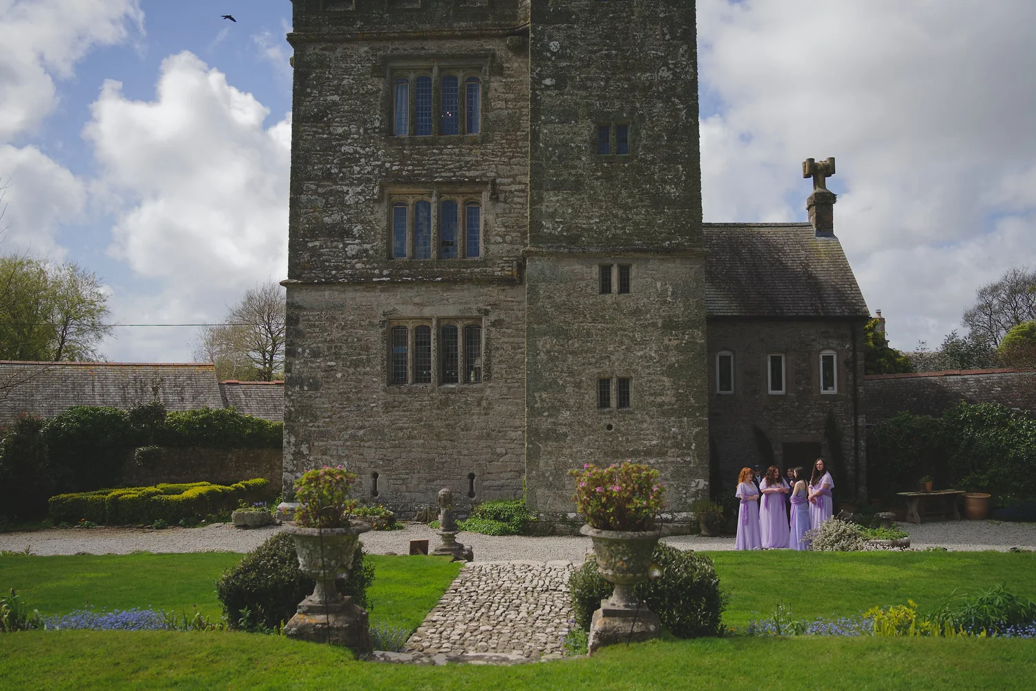 Bridesmaids in lilac waiting outside a Cornish manor house