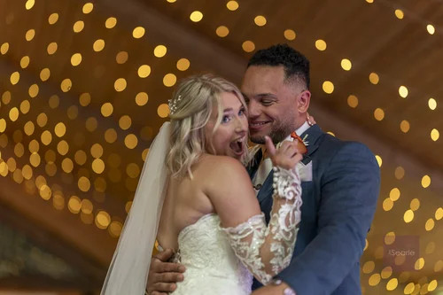 Bride pulling a delighted face mid-first-dance under the fairy lights