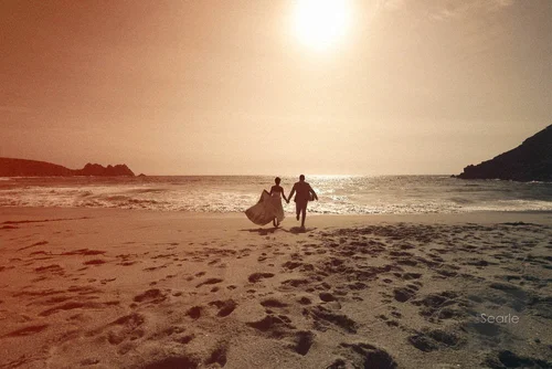 Bride and groom running hand in hand along the beach into the sunset