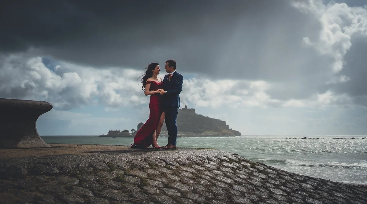 Bride in a red dress and groom in blue in front of St Michael's Mount