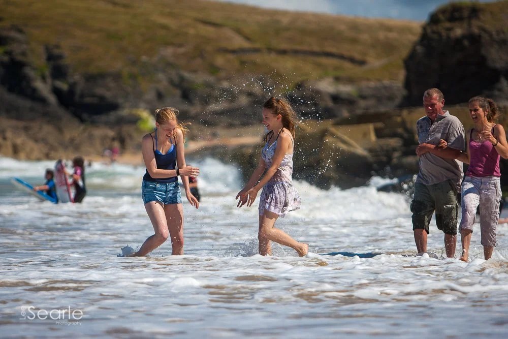 Family paddling and splashing in the surf on a Cornish beach during a natural family photo shoot