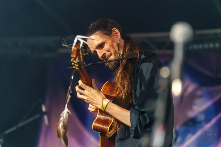 Long-haired musician lost in his guitar at a Cornish fairy festival