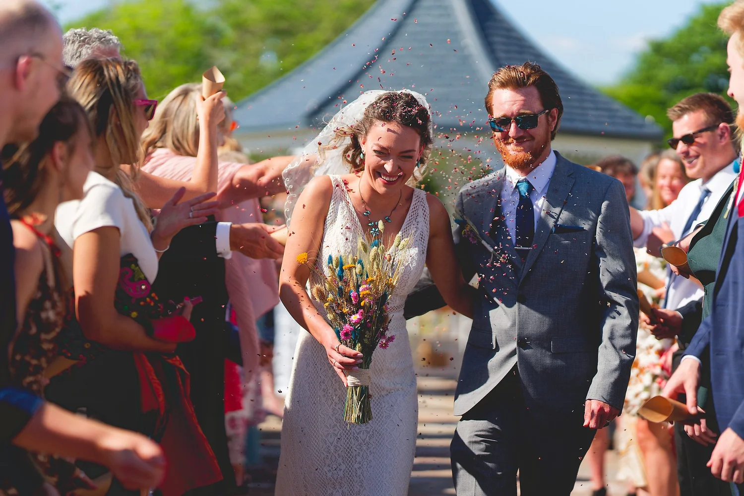 Newlyweds walking back down the aisle through a shower of confetti