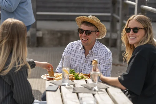 Friends laughing over lunch at a Cornwall food event, photographed for Seasonal Spuds