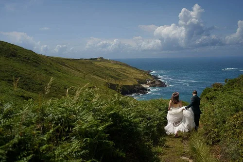 Bride and groom walking the coast path towards the sea