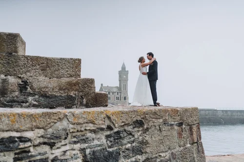 Newlyweds on the harbour wall at Porthleven, clock tower behind them in the mist