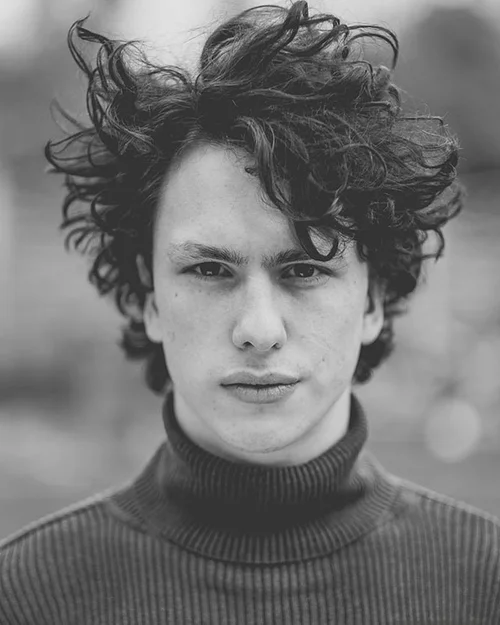 Black and white headshot of a young man with windswept curly hair, Cornwall headshot photographer