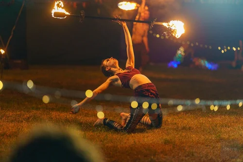 Fire performer arching backwards with a burning staff, Cornwall festival event photography